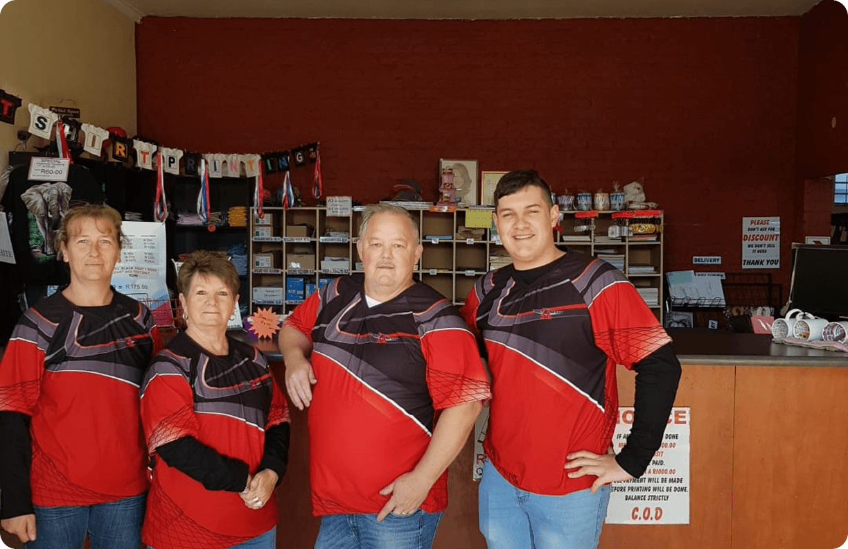 The Triangle Print Spot team, dressed in red shirts and blue jeans, stands confidently at their store counter.