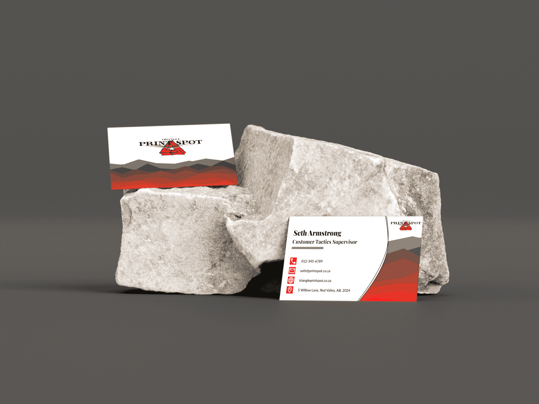 Business cards featuring a red and white design placed on a textured rock surface, showcasing a unique presentation style.